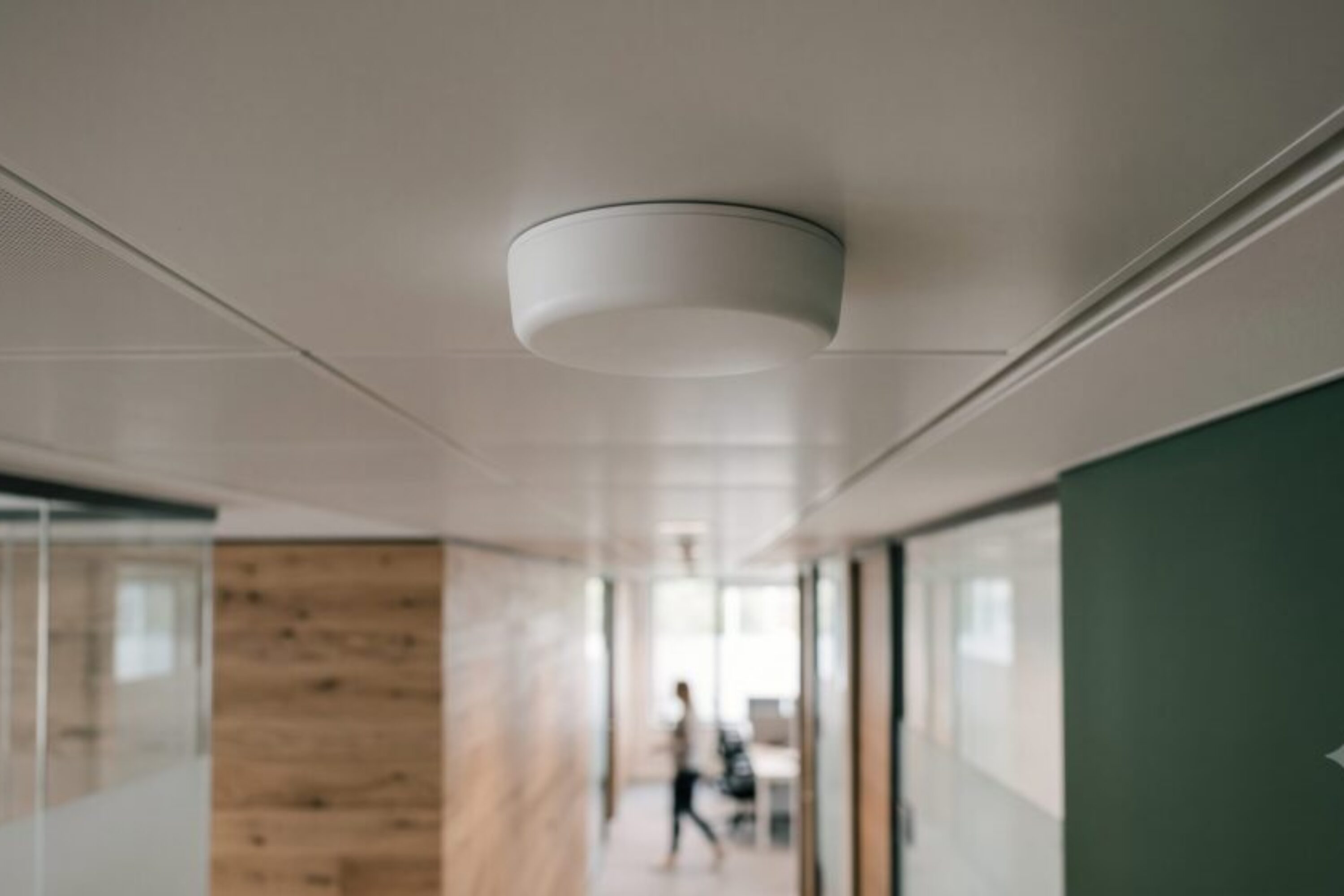 Compact ceiling-mounted mobile antenna unit in a modern office corridor